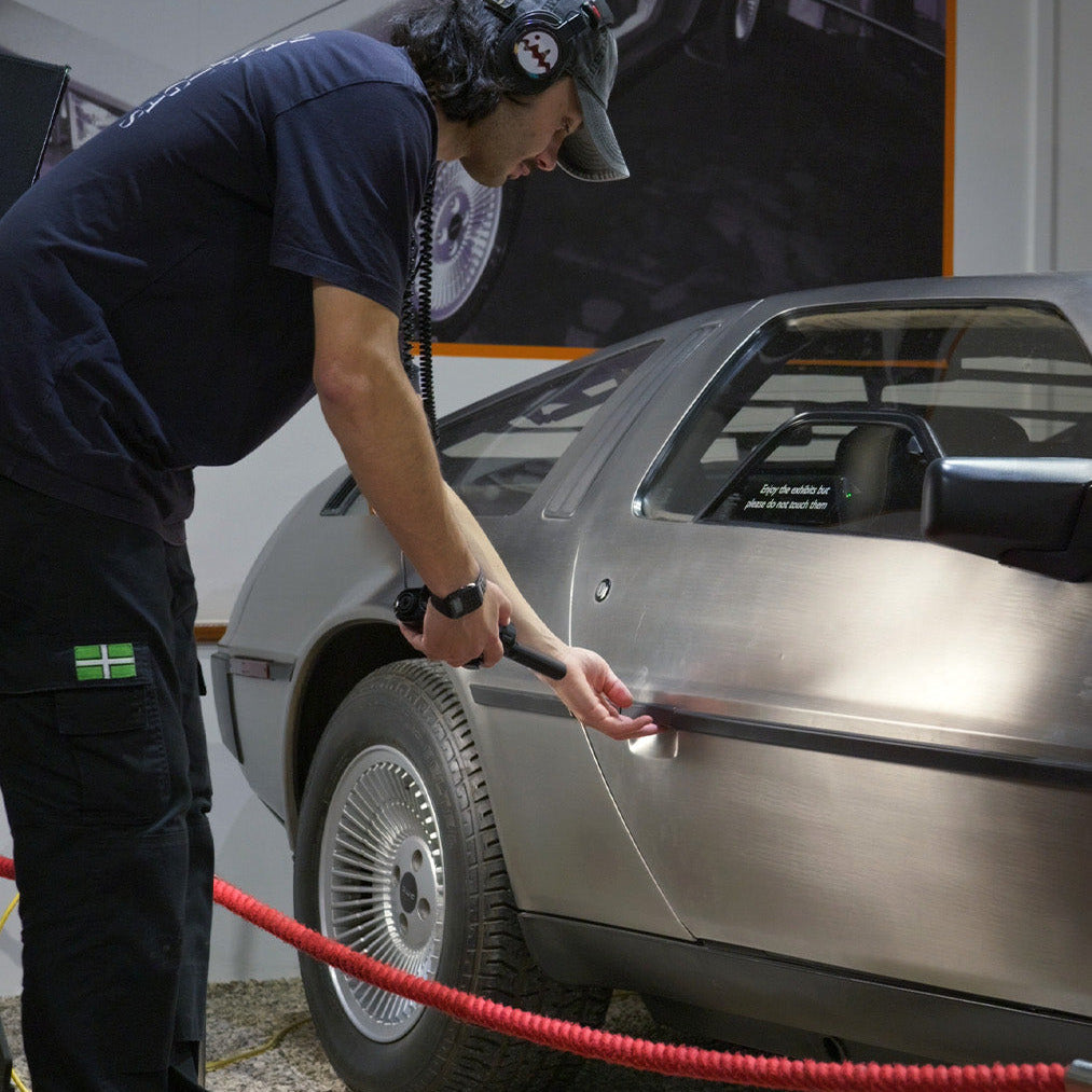 Person recording a DeLorean car with a microphone